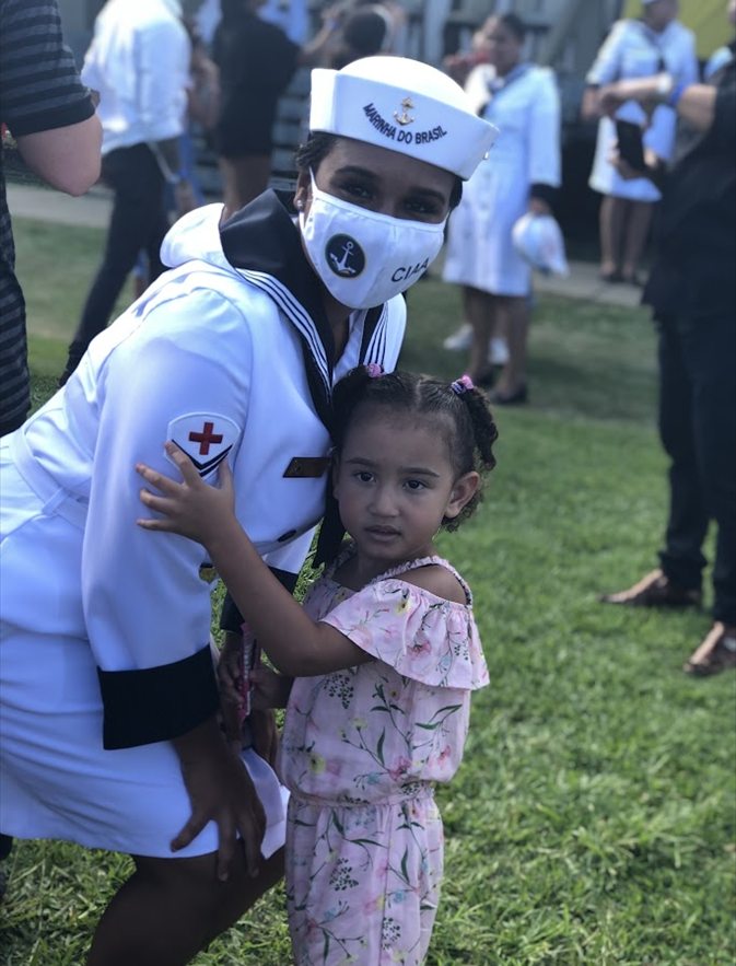 Luana fardada da Marinha do Brasil abraçando a filha em dia de cerimônia